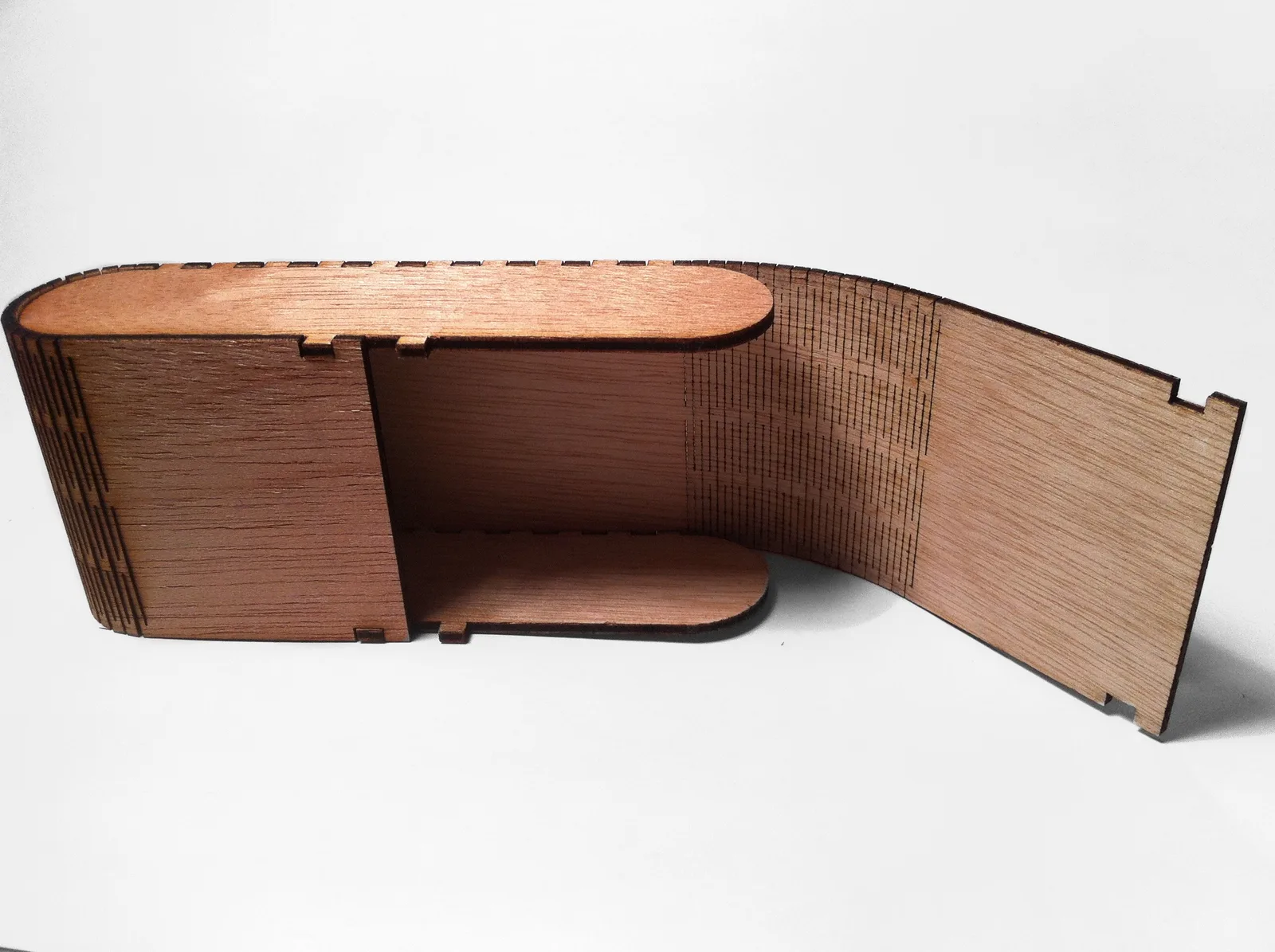 Caja de contrachapado abierta con una bisagra viva: cientos de cortes paralelos permiten que la tabla se curve