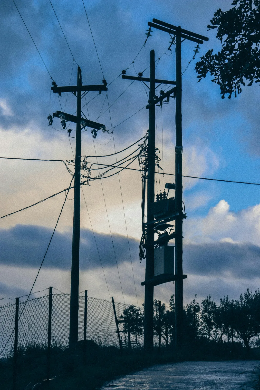 Postes de distribución con cables eléctricos contra un cielo nublado