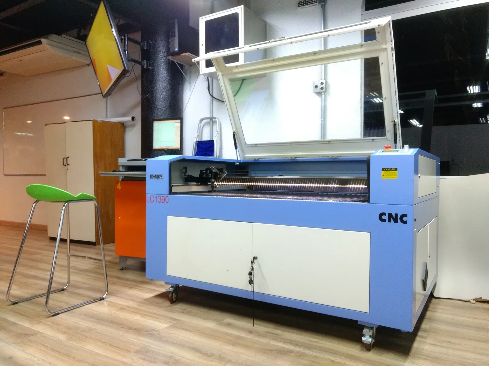 Máquina de corte láser CO2 de sobremesa grande, sobre ruedas, con la tapa abierta y la mesa de panal a la vista