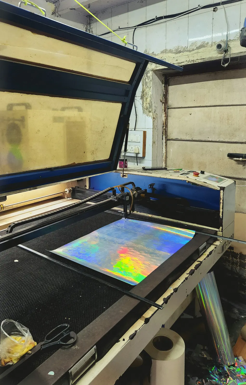 Máquina de corte láser CO2 cerrada de escritorio con la tapa abierta, grabando una lámina sobre su mesa de trabajo.