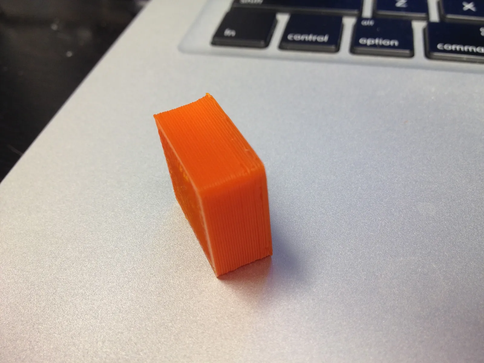 Pieza naranja recién despegada de la cama, con la primera capa aplastada contra el vidrio