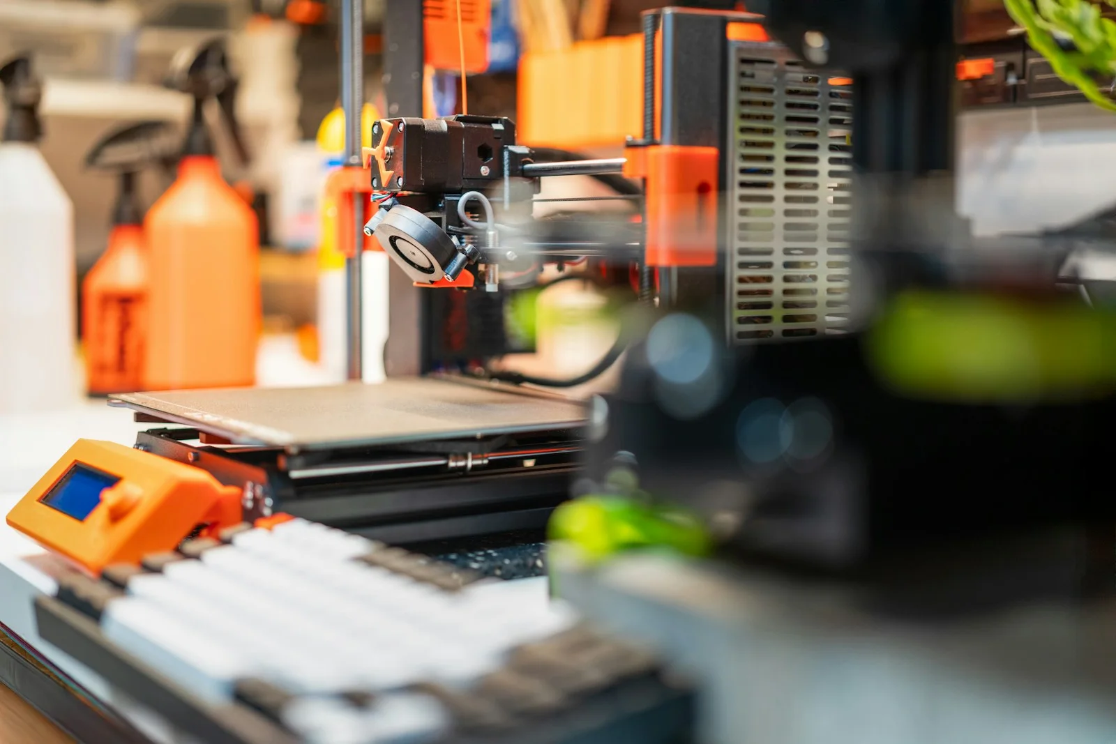 Impresora 3D de filamento con piezas naranjas trabajando en un banco de taller